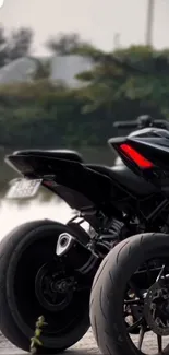 Sleek black motorcycle parked by a scenic outdoor lake.