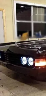 Sleek black muscle car with shining headlights in a garage.