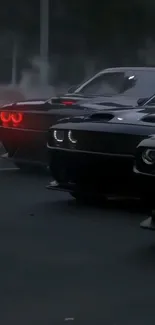 Black muscle cars with red taillights on a dark street at night.