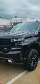 Black Chevrolet pickup truck parked in a lot with a cloudy sky.