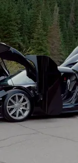 A sleek black sports car with open doors in a forest setting.