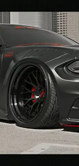 Close-up of sleek black sports car with red details on an urban road.