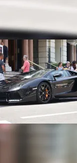 Sleek black sports car parked on city street, perfect for mobile wallpapers.