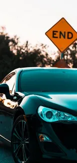 Black sports car at sunset with road sign in background.