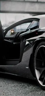 Sleek black sports car with open doors on an asphalt road.