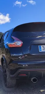 Black Nissan Juke against a blue sky background.