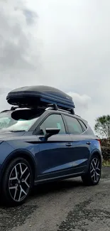 Blue SUV under cloudy sky with rooftop carrier.