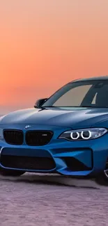 Blue sports car at the beach during a stunning sunset.