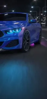 Sleek blue car driving at night with illuminated headlights.