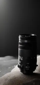 Sleek camera lens on a textured rock background in dark theme.