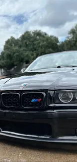 Front view of a classic black BMW car on a road.