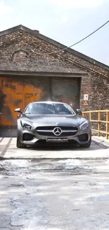 Gray Mercedes parked in an industrial garage with brick walls.