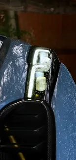 Close-up of a car headlight with raindrops on a sleek blue vehicle.