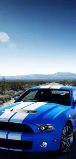 Blue sports car in desert landscape with clear blue sky.