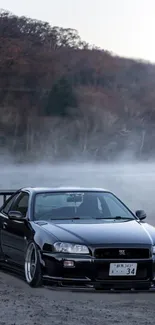 Black sports car in a misty forest landscape.