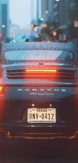 Sleek black sports car on a rainy city street at night.