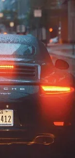 Sports car with glowing taillights in a rainy urban street.