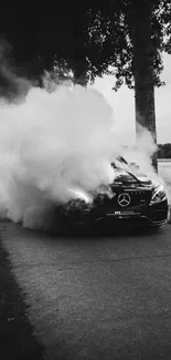 Monochrome photo of a car enveloped in smoke on a narrow forest pathway.