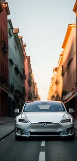 Sleek silver car drives down urban street at dusk, surrounded by colorful buildings.