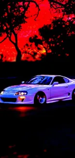 White sports car under red sunset with dark silhouettes of trees.