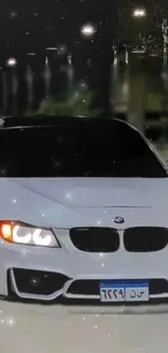 White sports car illuminated against a night city backdrop with glowing lights.