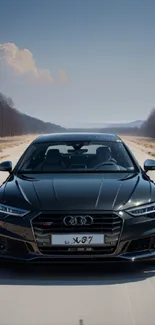 Black luxury car on a scenic open road with clear blue skies.