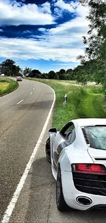 White sports car parked on scenic country road under blue sky.