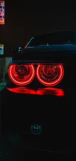 Car with glowing red tail lights in a dark urban setting.