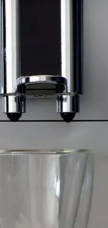 Sleek coffee machine with glass beneath.