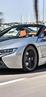 Sleek silver convertible car on open road with scenic background.