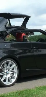 Sleek black convertible car with the roof open on a sunny day.