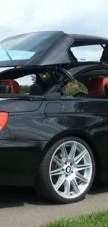 Sleek black convertible car with the roof down, showcasing a luxurious design.