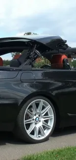 Black convertible car on road close-up with roof down.