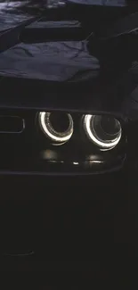 Dark car with sleek design and glowing headlights at night.