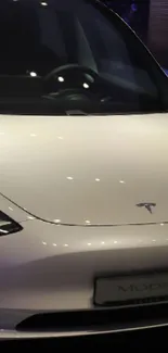 Sleek white Tesla car in showroom lighting.