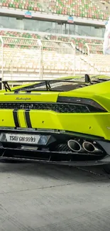 Green sports car on a race track, rear view.