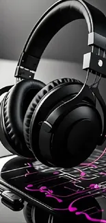 Black headphones resting on laptop with pink notes.