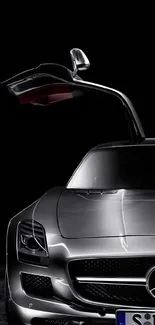 Sleek silver sports car with open gull-wing door on a black background.