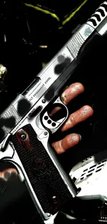 Black and metallic handgun held in hand with intricate details.