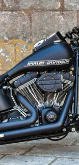 Sleek motorcycle engine with a matte black finish set against a stone background.