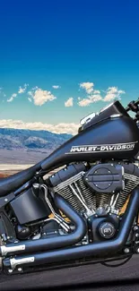 Motorcycle on a desert road with a bright blue sky and mountains.