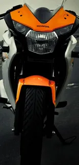 Front view of an orange and black motorcycle on a road.