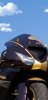 Sleek motorcycle against blue sky with white clouds.