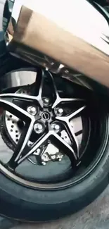 Closeup of a sleek motorcycle wheel with a shiny chrome appearance.