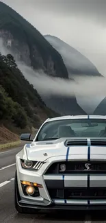 Sleek muscle car on a foggy mountain road with dramatic hills in the background.