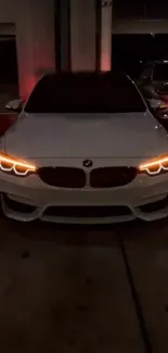 White BMW with glowing headlights in dark garage