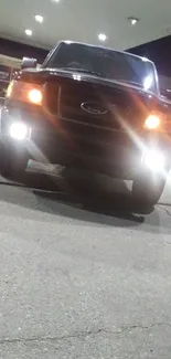 Nighttime truck at gas station with bright headlights.