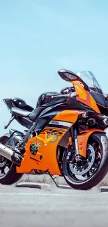 Orange sports motorcycle against clear sky.