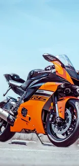 Sleek orange sport motorcycle against a clear sky.