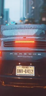 Porsche on a rainy street with city lights in the background.